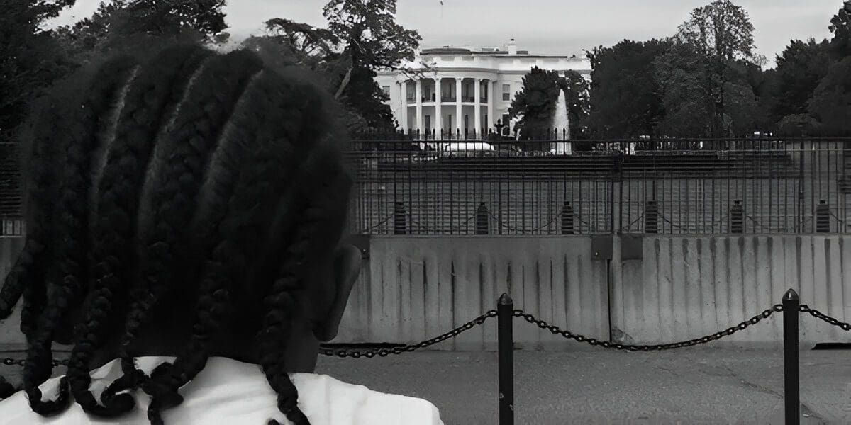 A person with dreadlocks standing in front of the white house.
