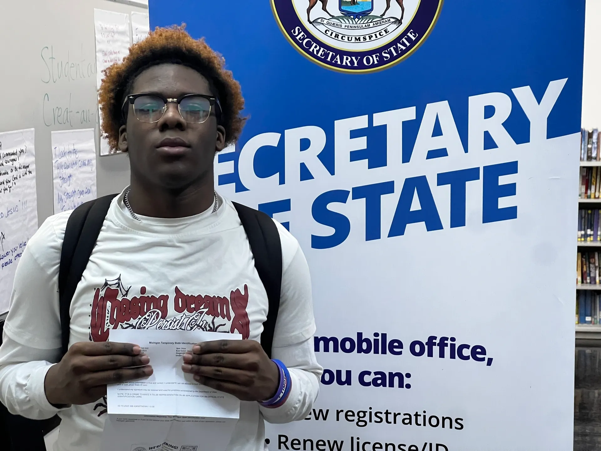A man holding papers in front of an official sign.