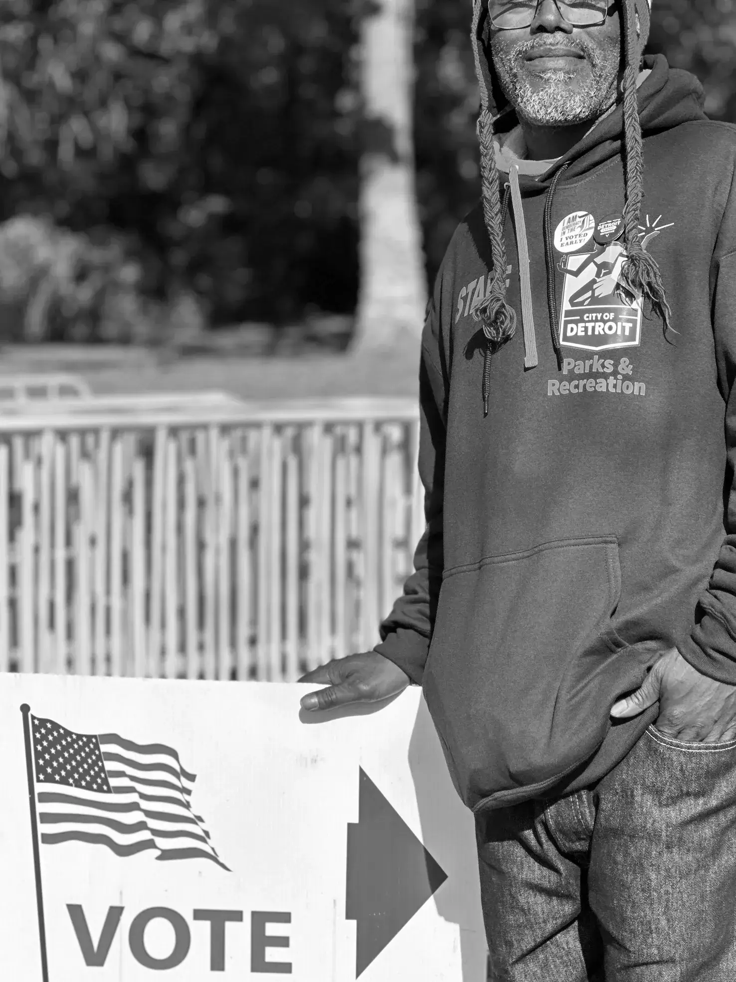 A man holding an american flag in front of a fence.
