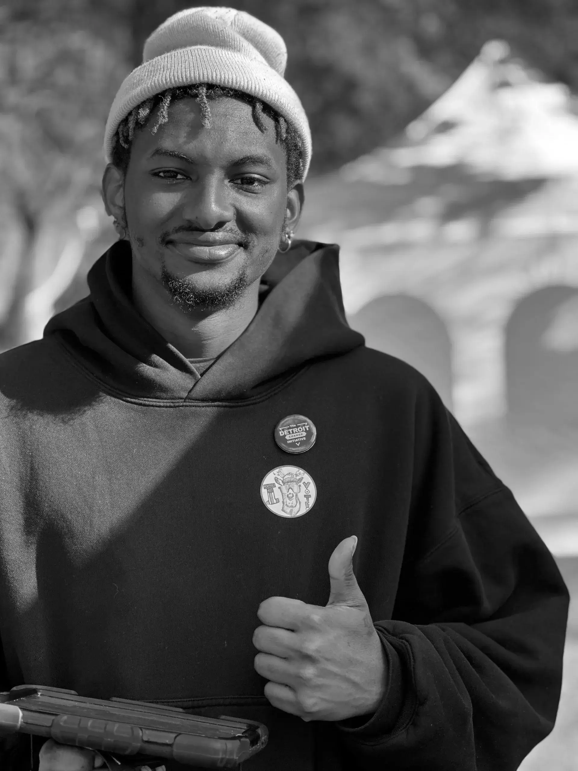 A man giving the thumbs up in front of trees.