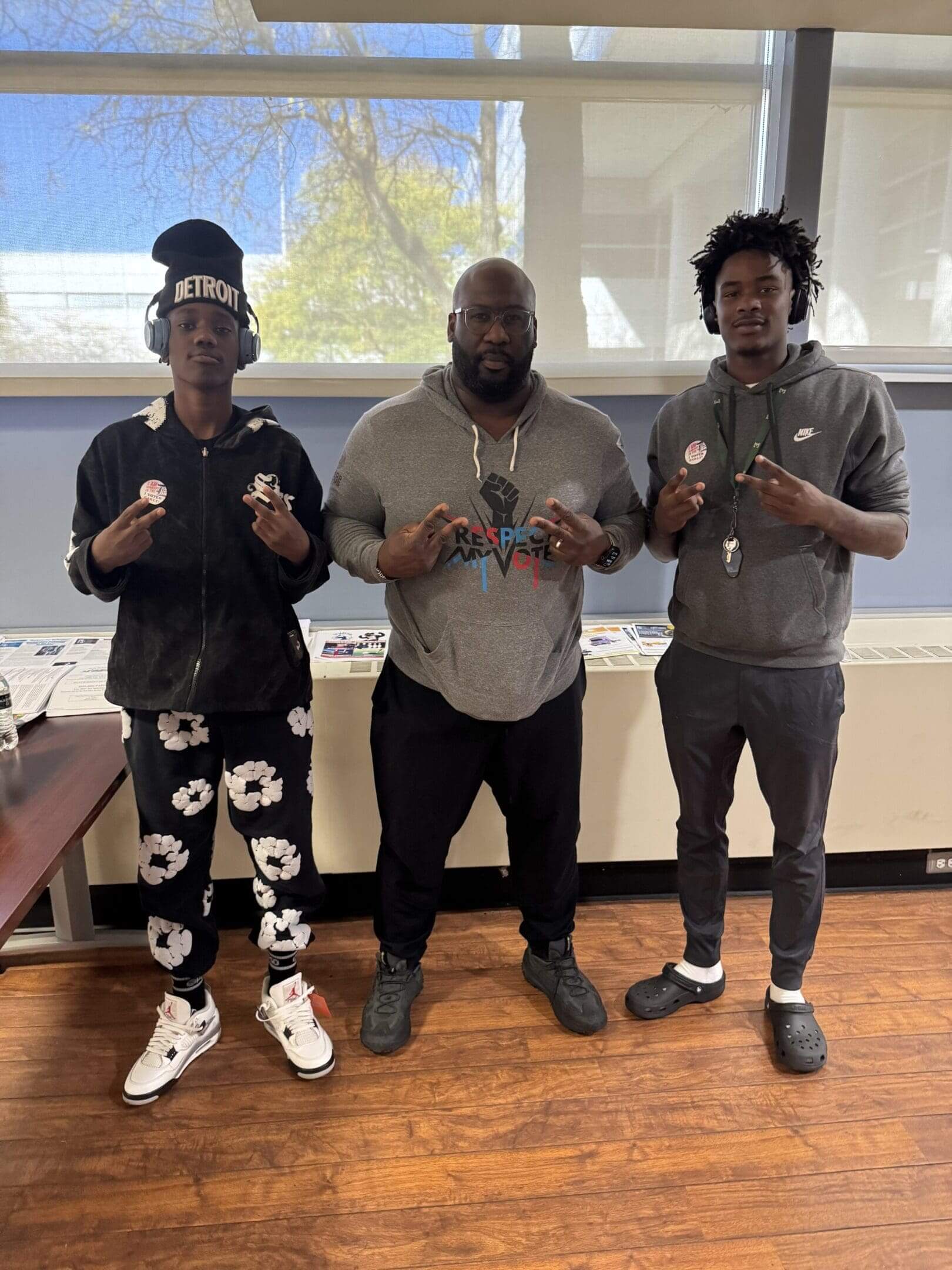 Three men posing indoors making hand signs